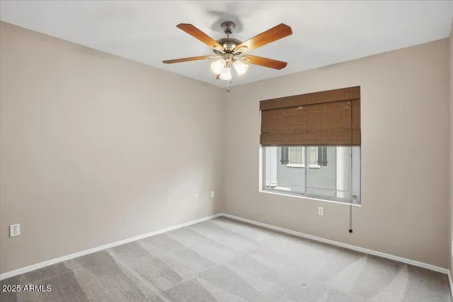 an empty room with a window and a ceiling fan