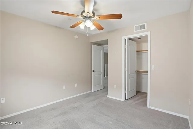 an empty room with closet and a chandelier fan