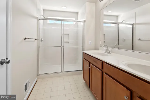 a bathroom with a double vanity sink a mirror and a shower