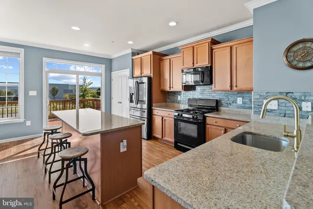 a kitchen with stainless steel appliances granite countertop a stove a sink a microwave a dining table and chairs