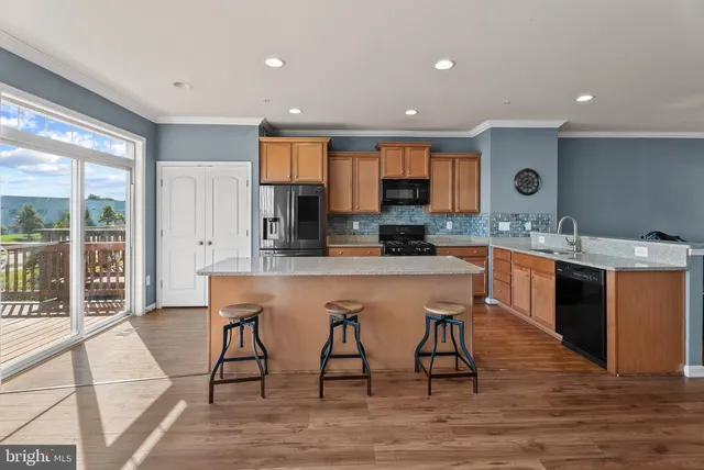 a kitchen with stainless steel appliances kitchen island granite countertop a stove a sink and a refrigerator