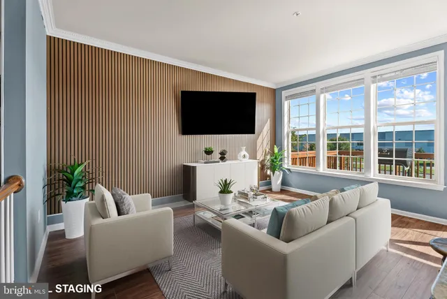 a living room with furniture floor to ceiling window and a flat screen tv
