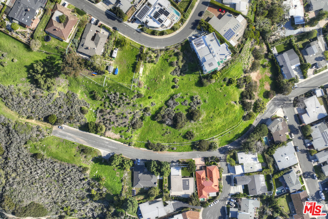 an aerial view of a residential houses with outdoor space and a street view