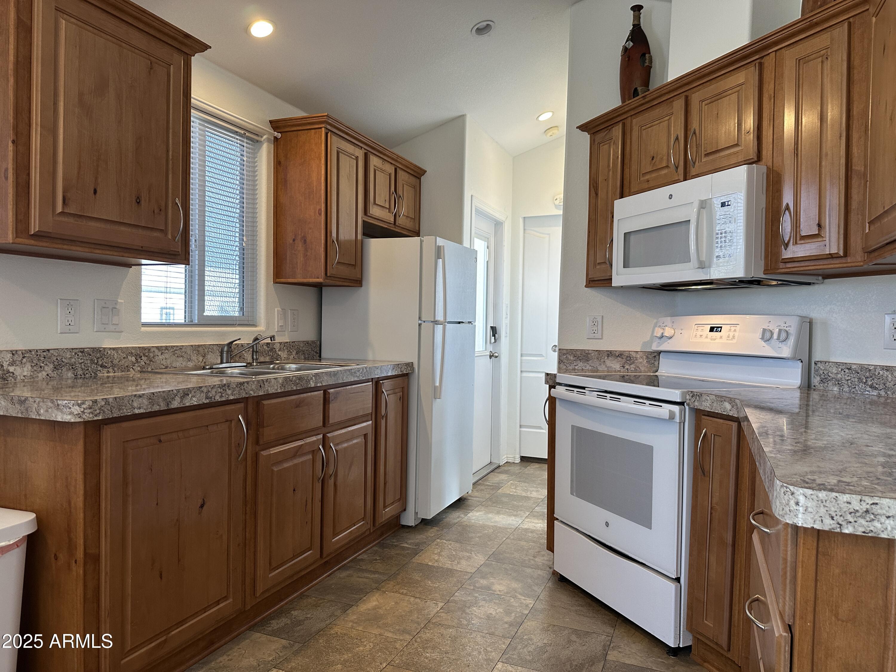 21245 Westward View Road, Unit 248 Congress, AZ 85332 - Photo 8 of 28 a kitchen with stainless steel appliances granite countertop wooden cabinets a stove a sink and a refrigerator