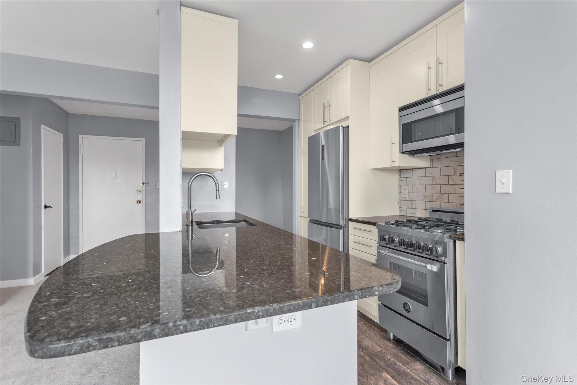 504 Merrick Road, Unit 4J Lynbrook, NY 11563 - Photo 9 of 28 a kitchen with stainless steel appliances granite countertop a stove a sink and a refrigerator