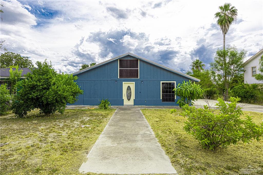 a backyard of a house with plants and large tree