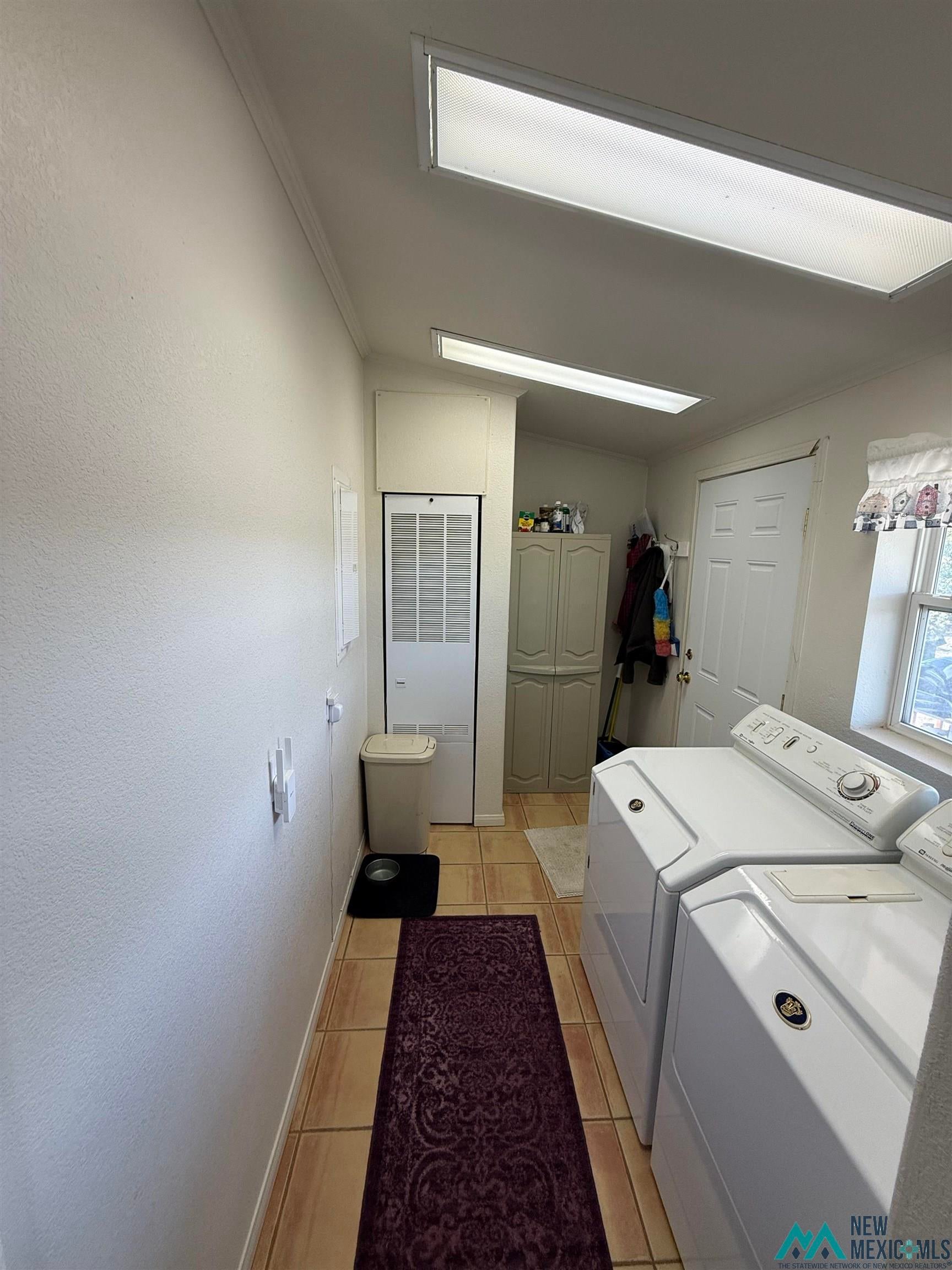 16 Overlook Road Los Ojos, NM 87551 - Photo 19 of 39 Laundry area featuring ornamental molding, washing machine and dryer, a heating unit, and light tile patterned flooring