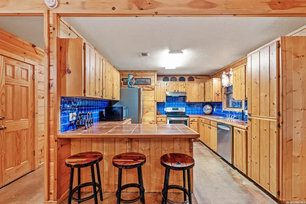 a kitchen with stainless steel appliances granite countertop a refrigerator a sink dishwasher and wooden cabinets with wooden floor