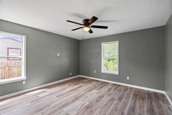 a view of empty room with wooden floor and fan