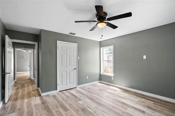 a view of empty room with wooden floor and ceiling fan