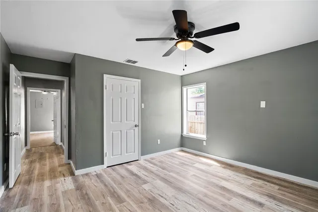 a view of empty room with wooden floor and ceiling fan