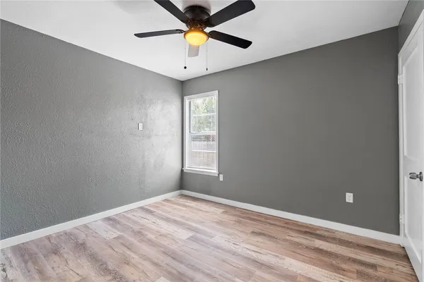 an empty room with a window and a fan