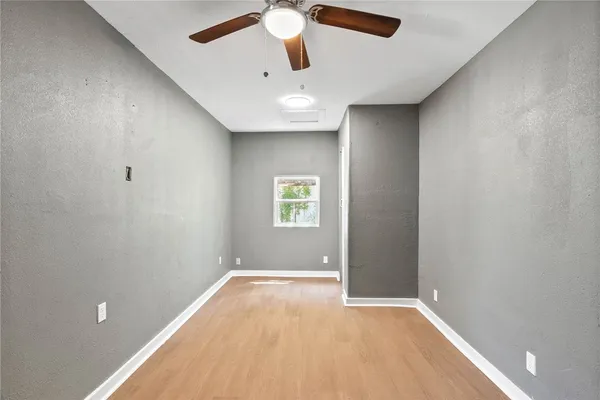 an empty room with ceiling fan and window
