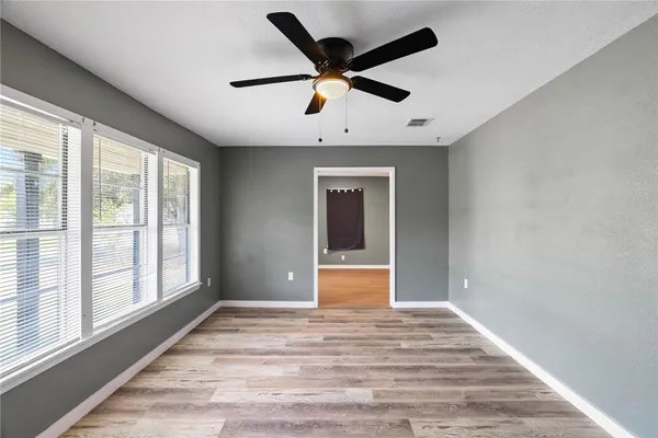 a view of empty room with wooden floor and fan