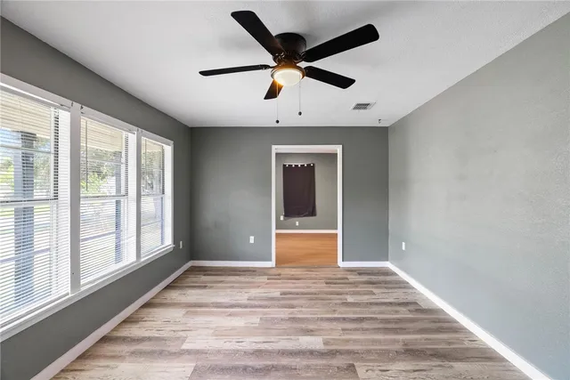 a view of empty room with wooden floor and fan