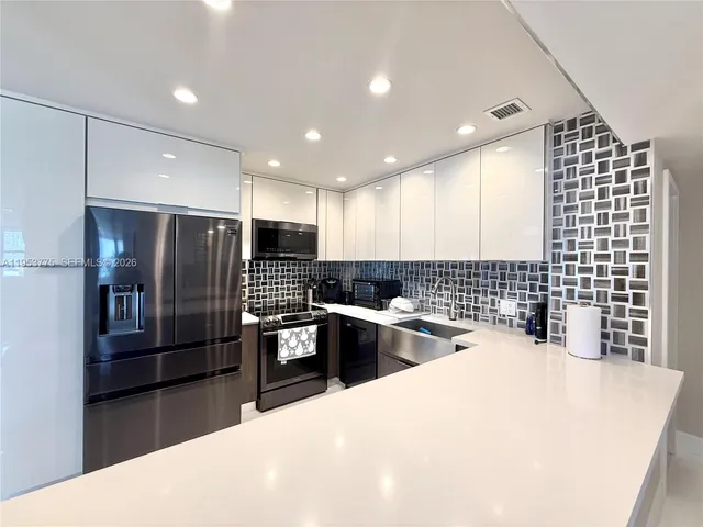 a kitchen with stainless steel appliances kitchen island granite countertop a refrigerator and a sink