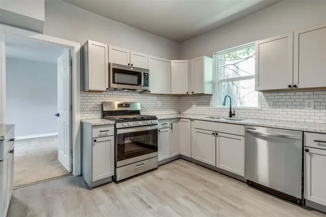 a kitchen with stainless steel appliances granite countertop a sink a stove a microwave and cabinets