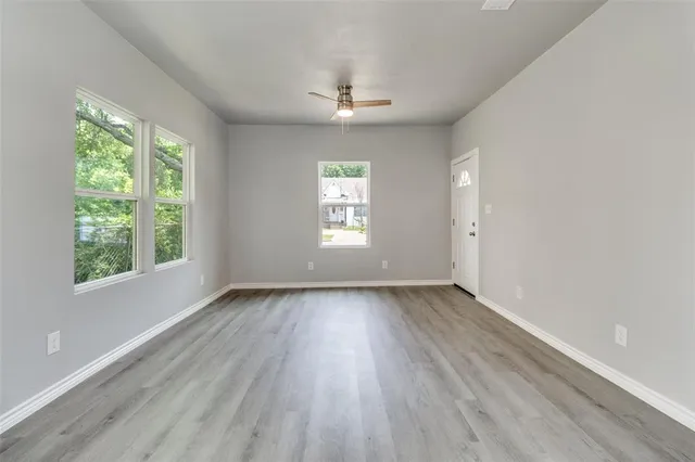 a view of an empty room with wooden floor and window