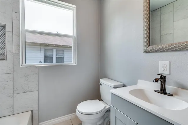 a bathroom with a toilet a sink a mirror and a window