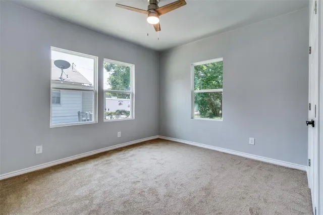 an empty room with windows and ceiling fan