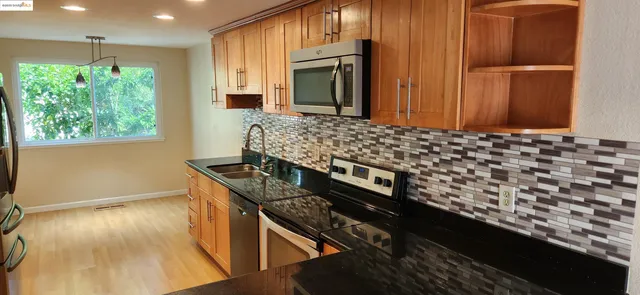 a kitchen with granite countertop a stove and a wooden floor