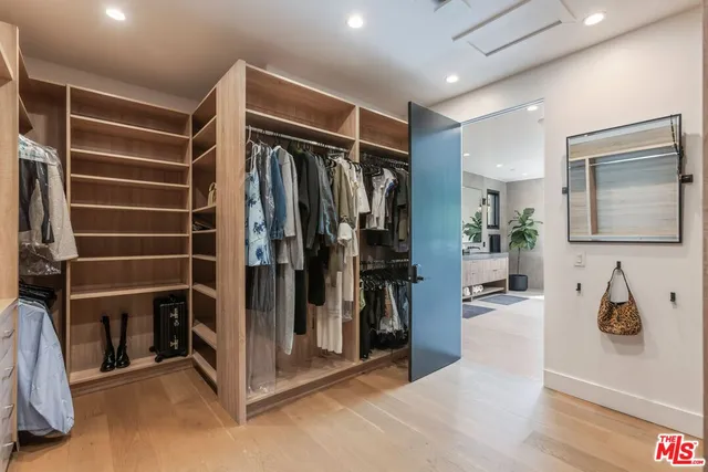 a view of walk in closet with clothes and shoes