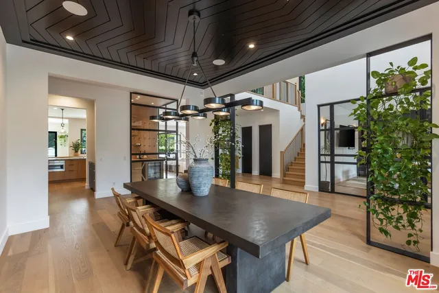 a dining room with wooden floor a chandelier a wooden table and chairs