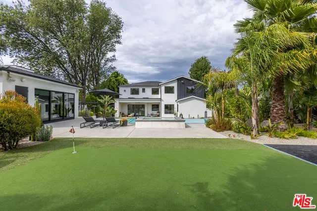 a view of yellow house with a yard and palm trees