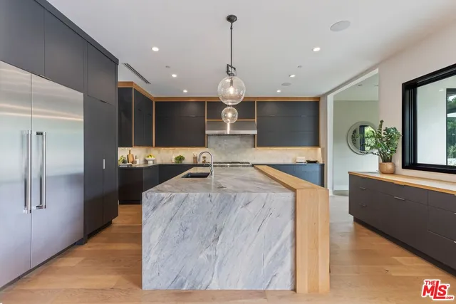 a large kitchen with kitchen island a large counter top stainless steel appliances and cabinets