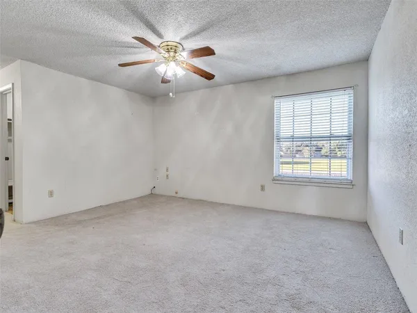 an empty room with windows and chandelier fan