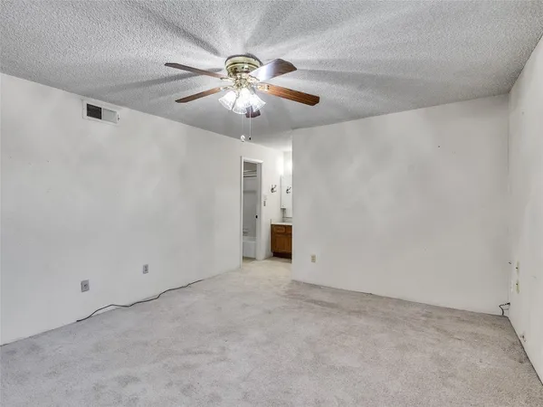 an empty room with chandelier fan and windows