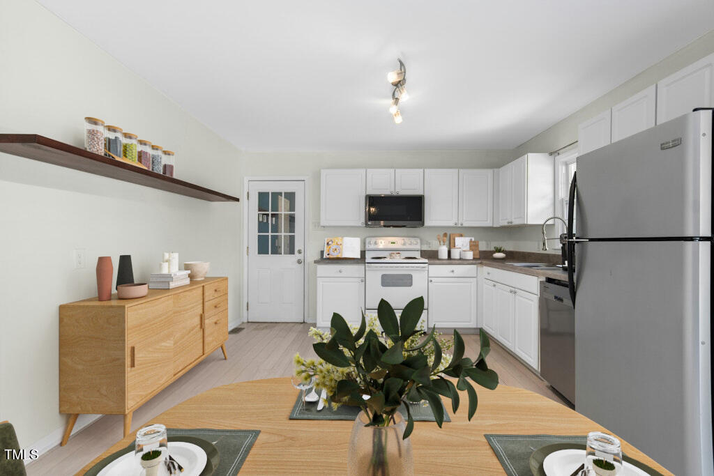 4021 Chaucer Drive Durham, NC 27705 - Photo 11 of 36 a kitchen with white cabinets and stainless steel appliances