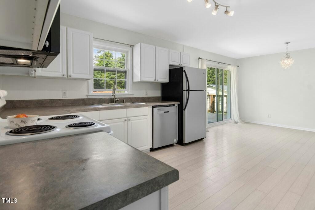 4021 Chaucer Drive Durham, NC 27705 - Photo 15 of 36 a kitchen with stainless steel appliances a sink a stove a refrigerator cabinets and a window