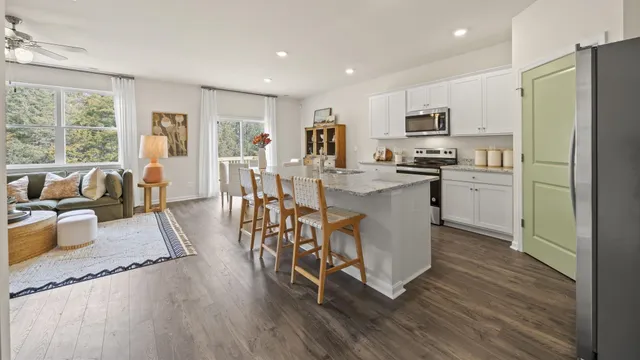 a kitchen with stainless steel appliances a stove a sink a refrigerator white cabinets and wooden floor