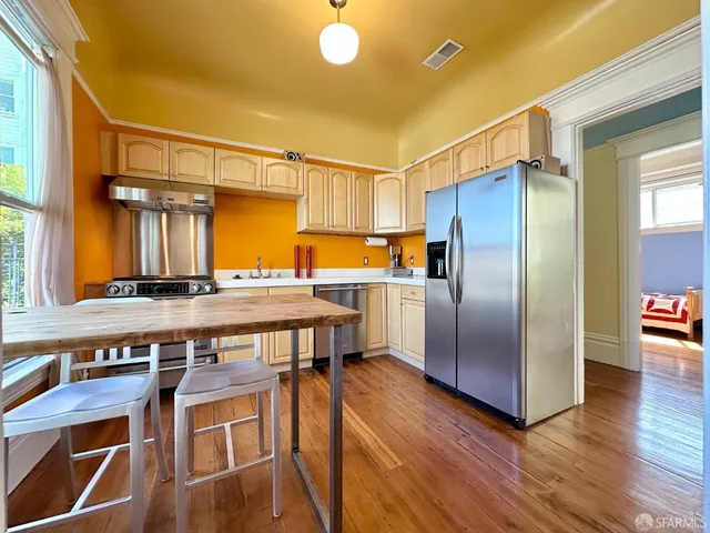 a kitchen with stainless steel appliances a stove a refrigerator and wooden floor