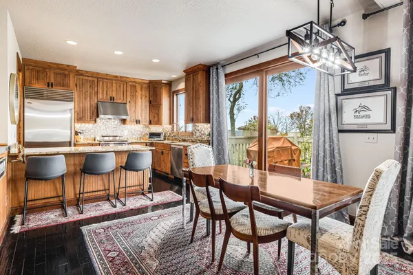 a kitchen with stainless steel appliances granite countertop a stove top oven a refrigerator a sink and a dining table with granite countertops