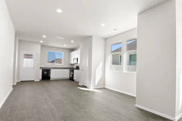 a view of an empty room with wooden floor and windows