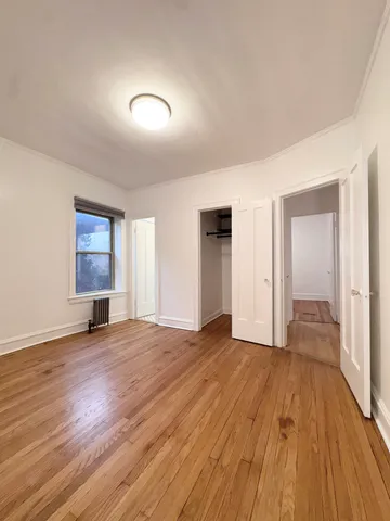 a view of empty room with wooden floor and window