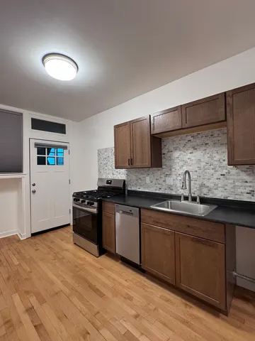 a kitchen with stainless steel appliances granite countertop a sink and cabinets with wooden floor