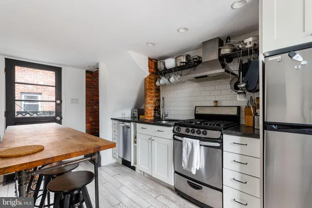 a kitchen with stainless steel appliances a stove a table and chairs
