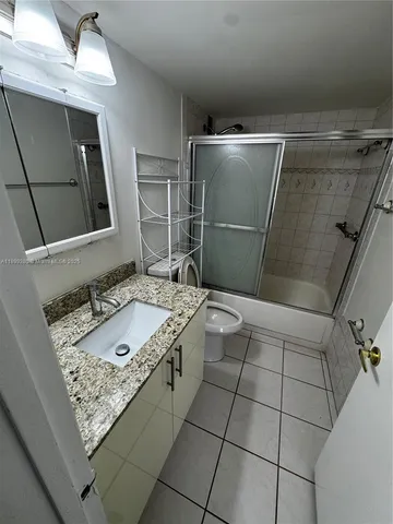 a bathroom with a granite countertop sink a toilet and mirror