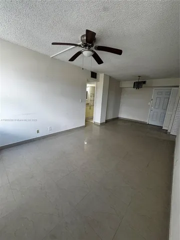 an empty room with a ceiling fan and window