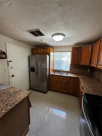 a kitchen with granite countertop a refrigerator and a stove top oven