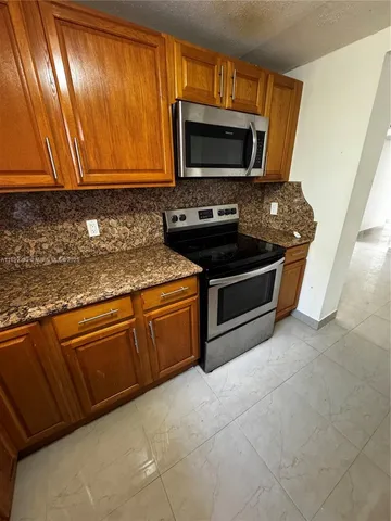 a kitchen with granite countertop cabinets stainless steel appliances and a window