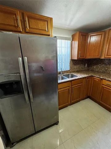 a kitchen with stainless steel appliances granite countertop a sink and a refrigerator