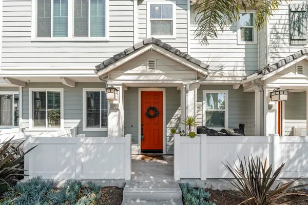 a view of the house with potted plants and a large tree