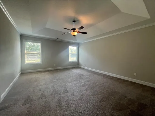 an empty room with windows and chandelier fan