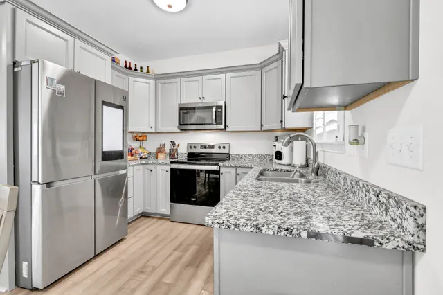 a kitchen with kitchen island granite countertop a refrigerator stove top oven and sink