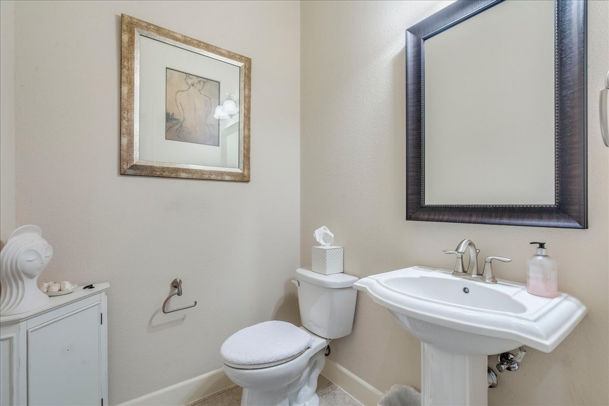 12909 Medina River Way Austin, TX 78732 - Photo 30 of 36 A classic pedestal sink anchored beneath a dark framed mirror defines this neutral powder room.