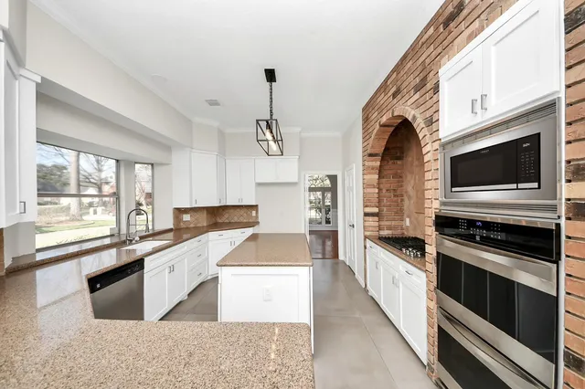 a large kitchen with granite countertop a stove top oven a sink a counter space and cabinets